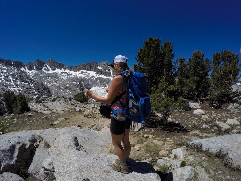 Woman reading map surrounded by alpine mountains with patches of snow